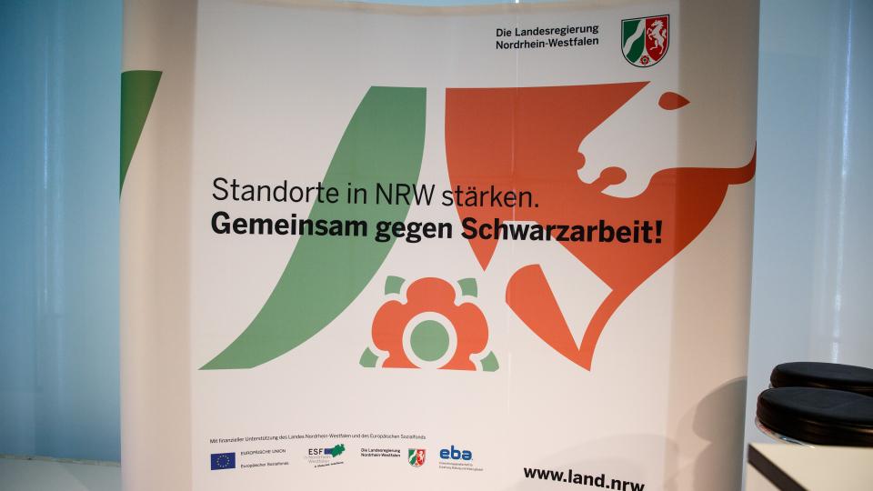 Foto zeigt Aufsteller mit dem Titel "Standorte in NRW stärken - Gemeinsam gegen Schwarzarbeit"