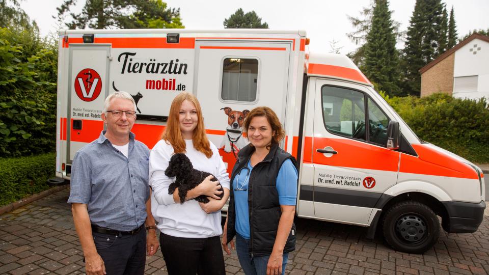 Gesamtfoto: Coach des Projekt, Auzubildende und Tierärztin, im Hintergrund die mobile Tierarztpraxis