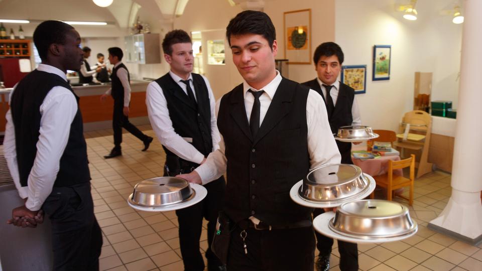 Foto: Junger Kellner mit drei Teller in der Hand