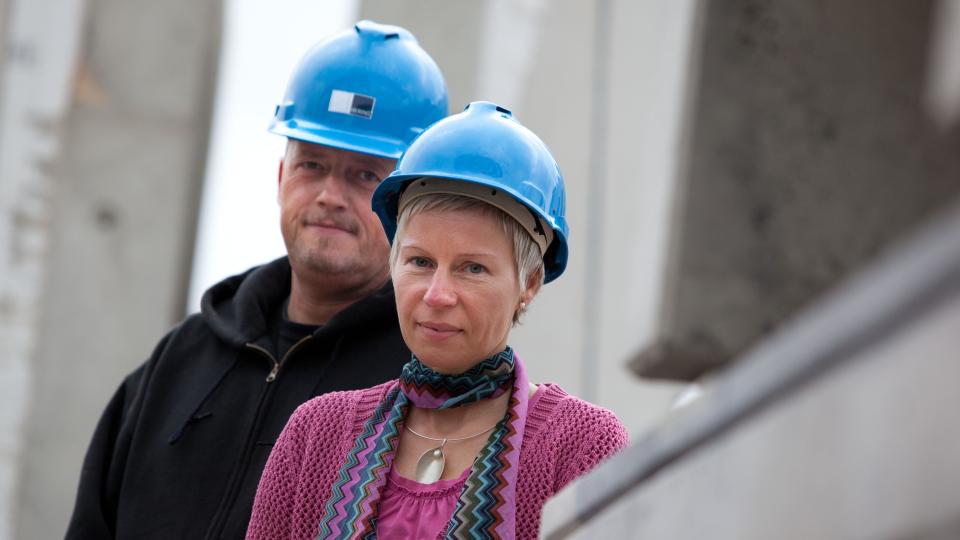 Mann und Frau mit Helm auf Baustelle