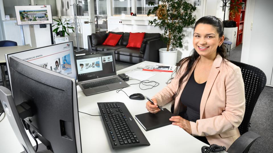 Junge Frau sitzt am Computerarbeitsplatz vor zwei Monitoren