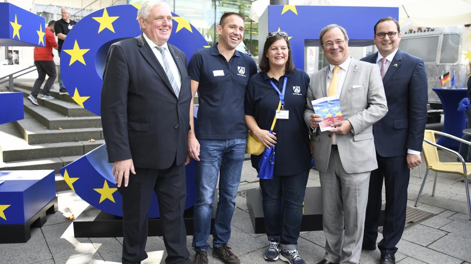 ESF-Stand Minister Laumann (li) und Ministerpräsident Laschet (2.v.r.) vor blauen Großbuchstaben ESF mit gelben Sternchen