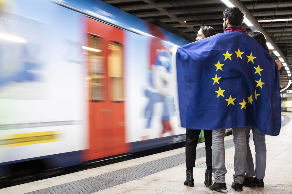 Jugendliche mit EU-Flagge auf Bahnsteig