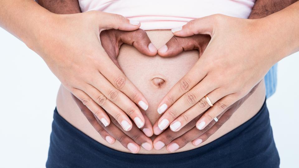 Hände auf schwangerem Bauch einer Mutter