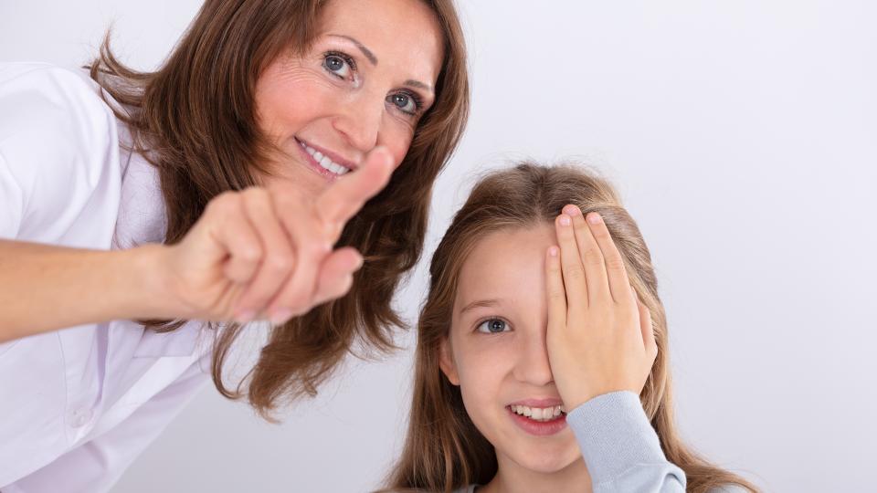 Lächelnde Augenärztin hilft Mädchen bei der Sehkontrolle
