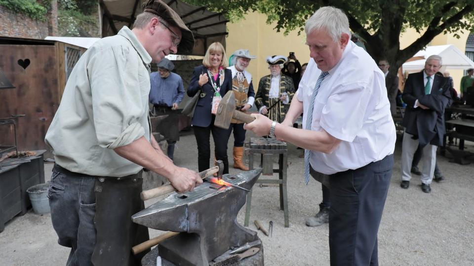 Minister Laumann haut bei seinem Besuch auf dem Flachsmarkt in Krefeld-Linn mit einem Hammer auf einen Amboss