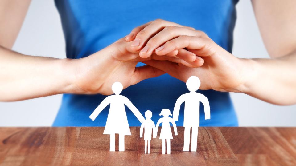 Eine Frau hält ihre Hände über eine Scherenschnittfamilie