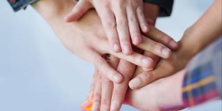 übereinanderliegende Hände als Symbol für Gemeinschaft