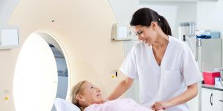 Eine Patientin auf einer CT-Liege wird von einer Krankenschwester betreut
