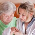 Eine Pflegekraft hält die Hand einer älteren Dame 